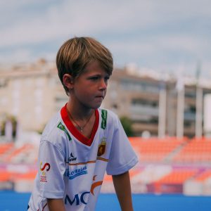 niño jugando a hockey hierba en el estadio de terrassa con la camiseta blanca del equipo nacional