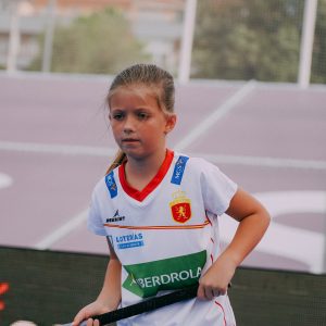 niña con un palo de hockey y la camiseta talla junior de las redsticks
