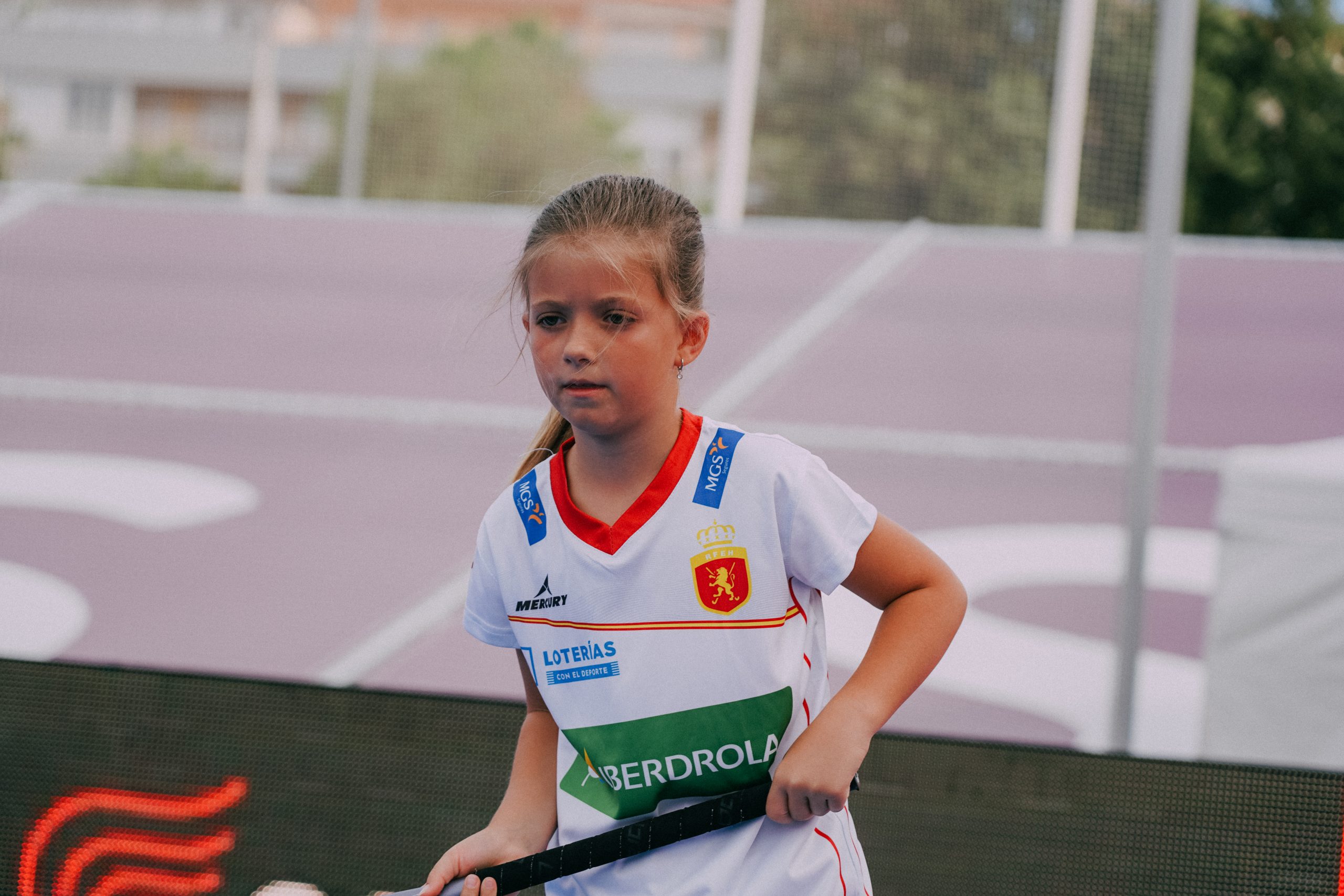 niña con un palo de hockey y la camiseta talla junior de las redsticks