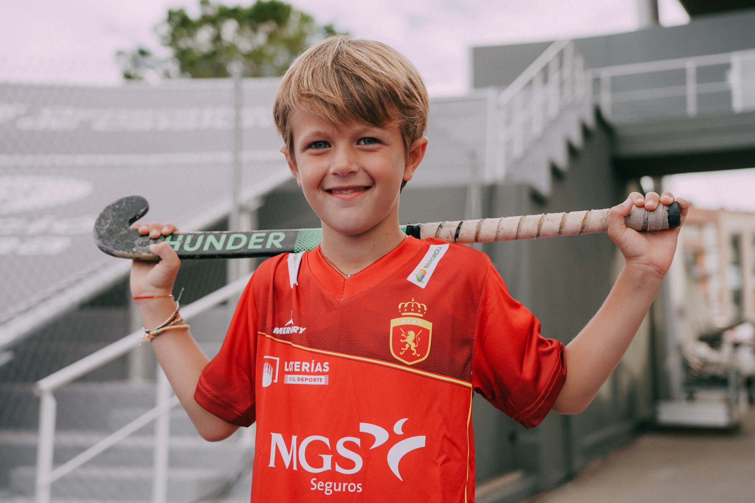 niño con el stick de hockey en la espalda con camiseta roja de los redsticks