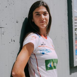 Chica apoyada en la pared con la camiseta blanca de las redsticks de hockey hierba