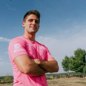 Chico de brazos cruzados posando con la camiseta exclusiva rosa solidaria de los redsticks
