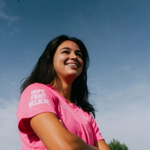 jugadora de la selección de hockey mirando a lo lejos con la camiseta solidaria redsticks en favor de la lucha contra el cancer de mama y con las palabras HOPE FIGHT BELIEVE en la manga derecha