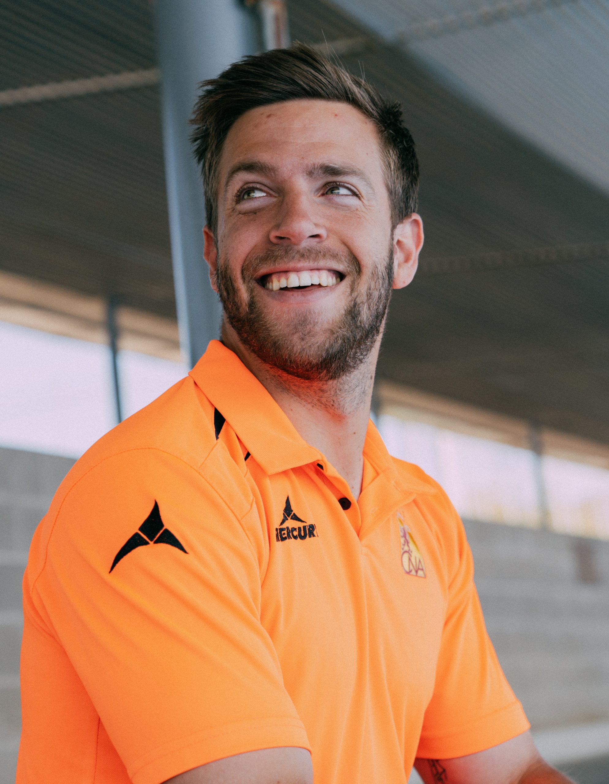 Hombre sonríe con el polo de árbitraje naranja fosforito de hockey hierba