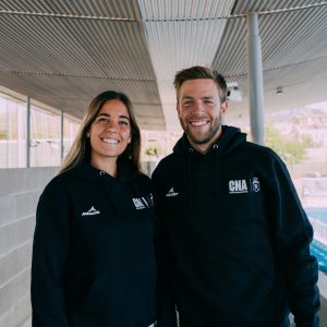Chico y chica posan con ropa oficial de Mercury para árbitros de hockey hierba. Sudadera azul marino unisex del Comité Nacional de Árbitros